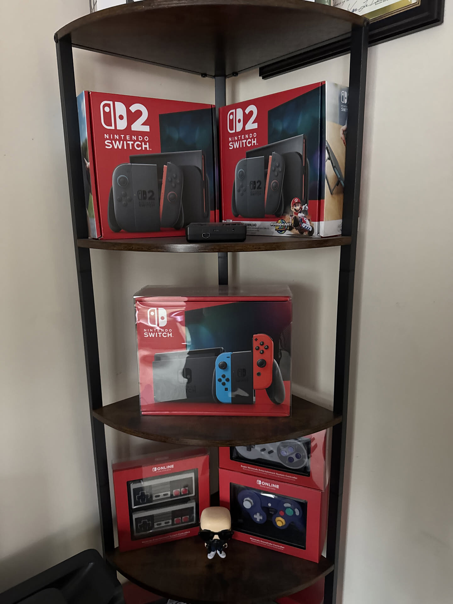 Two boxed Nintendo Switch 2 consoles, a boxed original Switch and Nintendo Switch Online retro controllers on a shelf